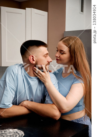 Couple enjoying a moment together in a kitchen while sharing smiles and affection during the day Couple enjoying a moment together in a kitchen while sharing smiles and affection during the day 138034914