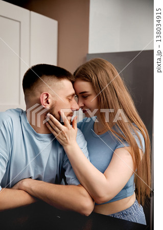 Couple shares a moment together at home during a casual afternoon in the kitchen with warm light and simple surroundings Couple shares a moment together at home during a casual afternoon in the kitchen with warm light and simple surroundings 138034915