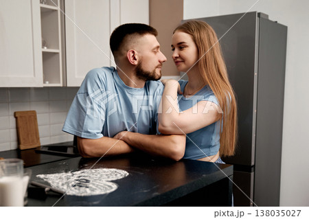 Couple enjoys time together in a kitchen while preparing food and sharing moments of affection in their home during the afternoon Couple enjoys time together in a kitchen while preparing food and sharing moments of affection in their home during the afternoon 138035027
