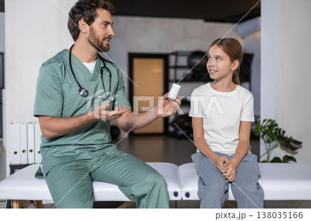 Male doctor discussing vitamins with young girl 138035166
