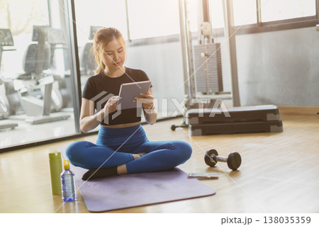 sport healthy asian women sitting in gym fitness using tablet, learning online sports training sport healthy asian women sitting in gym fitness using tablet, learning online sports training 138035359