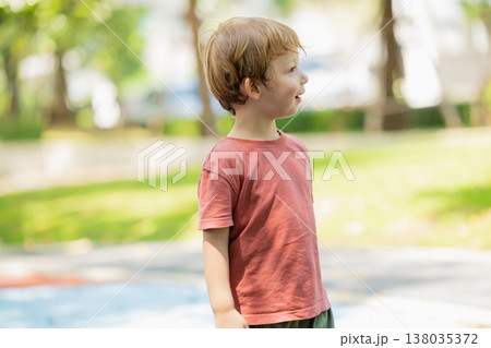 A cute little boy stands in the garden park outdoor, looking excited and surprised expression. A cute little boy stands in the garden park outdoor, looking excited and surprised expression. 138035372