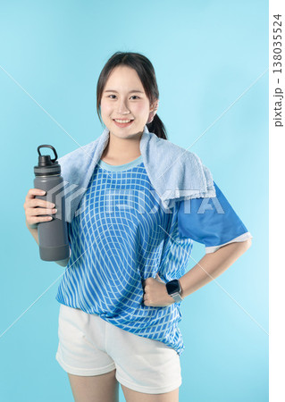 Happy sport woman asian teen holding a water bottle and a towel standing smile isolated in studio 138035524