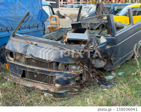 Front section of damaged van with missing parts and rusted body panels in open lot. Scrapyard salvage, mechanical deterioration, vehicle dismantling, repair economics, abandonment and material Front section of damaged van with missing parts and rusted body panels in open lot. Scrapyard salvage, mechanical deterioration, vehicle dismantling, repair economics, abandonment and material 138036041