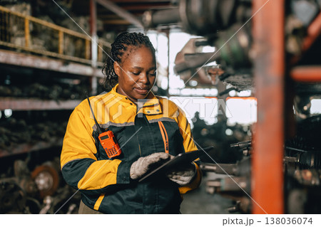 Happy Black African women engineer worker enjoy working in old used machine part stock warehouse. 138036074