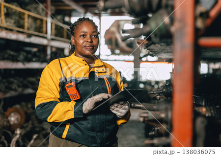 Happy Black African women engineer worker enjoy working in old used machine part stock warehouse. 138036075