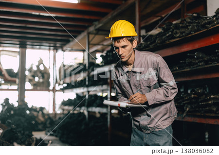 Engineer technician male worker work in old used machine part stock warehouse. 138036082