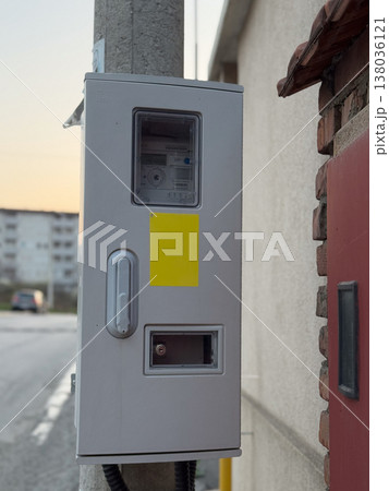 Electricity meter box mounted on exterior wall near residential street. Utility infrastructure, energy measurement, consumption monitoring, service connection, urban supply system, household Electricity meter box mounted on exterior wall near residential street. Utility infrastructure, energy measurement, consumption monitoring, service connection, urban supply system, household 138036121