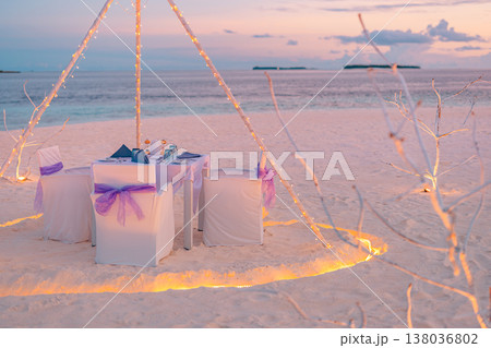 Romantic beach dinner with lights and flowers, ocean view, vibrant colorful sky and clouds, dreamy tropical evening Romantic beach dinner with lights and flowers, ocean view, vibrant colorful sky and clouds, dreamy tropical evening 138036802