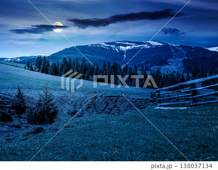 mountainous countryside landscape in spring at night. full moon over wooden fence and grassy meadow on a green hill. distant mountain ridge with snow capped tops. mysterious cloudy sky mountainous countryside landscape in spring at night. full moon over wooden fence and grassy meadow on a green hill. distant mountain ridge with snow capped tops. mysterious cloudy sky 138037134