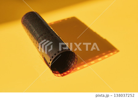 Film strip laying unrolled with shadow reflecting its iconic perforations Film strip laying unrolled with shadow reflecting its iconic perforations 138037252