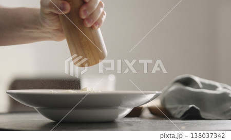 man add dry seasoning of italian herbs over cheese to pasta into plate closeup 138037342