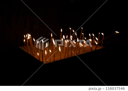 Burning candles in church on black background Burning candles in church on black background 138037546