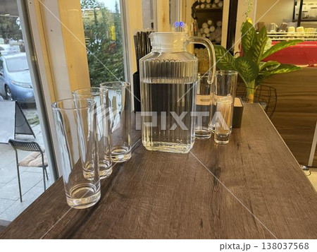 a brown wooden table with glasses and jar of water 138037568