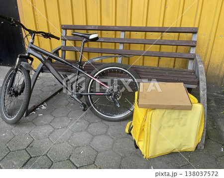 yellow backpack near the bike on the sidewalk. delivery concept yellow backpack near the bike on the sidewalk. delivery concept 138037572