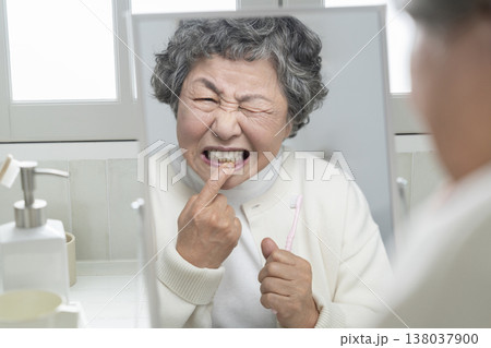 歯磨きの途中で歯茎を気にするシニア女性 138037900