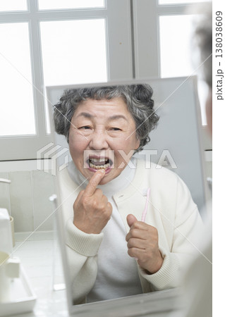 鏡を見ながら歯茎を気にするシニア女性 鏡を見ながら歯茎を気にするシニア女性 138038609