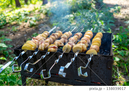 Potatoes with lard are grilled on a skewer over open flames, creating a rustic and flavorful outdoor meal. Potatoes with lard are grilled on a skewer over open flames, creating a rustic and flavorful outdoor meal. 138039017