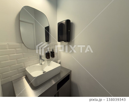 Modern restroom sink area with mirror, faucet, soap dispensers, and paper towel unit. Hygiene maintenance, public bathroom design, sanitation routine, and functional interior organization for daily 138039343