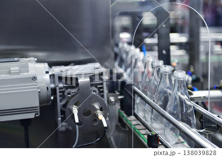 Conveyor belt with empty glass bottles in a modern bottling factory line Conveyor belt with empty glass bottles in a modern bottling factory line 138039828