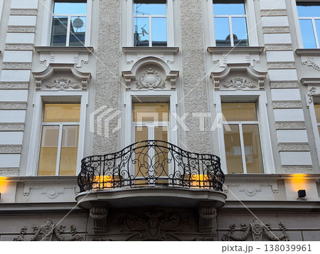 Ornate historic facade with wrought iron balcony and tall windows in the old town. Architectural symmetry, heritage ornamentation, urban elegance, and restored European streetscape detail Ornate historic facade with wrought iron balcony and tall windows in the old town. Architectural symmetry, heritage ornamentation, urban elegance, and restored European streetscape detail 138039961