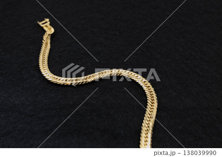 黒背景にS字に置かれたゴールドの喜平ブレスレット 138039990