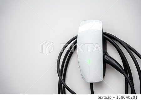 Electric car charging on parking lot with electric car charging station on city street. Close up of power supply plugged into an electric car being charged. 138040201