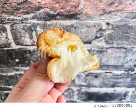 手で持ったふわふわのシュークリーム。バニラクリーム入り。 手で持ったふわふわのシュークリーム。バニラクリーム入り。 138040892