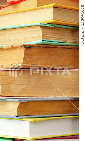 Books stacked on a table showing worn spines and pages in a reading area 138041058