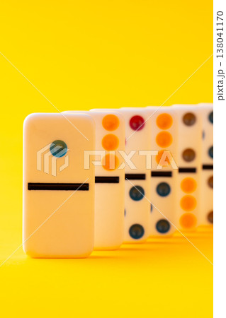 Bright yellow background shows classic dominoes arranged in a row with different designs Bright yellow background shows classic dominoes arranged in a row with different designs 138041170