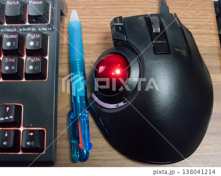 使い込んだキーボードの横に多色ボールペンと高機能トラックボール 138041214