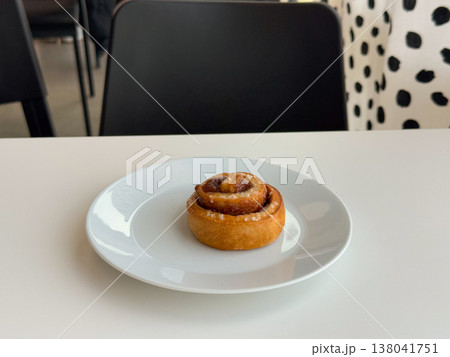 Cinnamon roll pastry dusted with sugar served on white plate against minimal background. Bakery product styling, sweet breakfast idea, cafe menu item, dessert simplicity, clean food presentation 138041751
