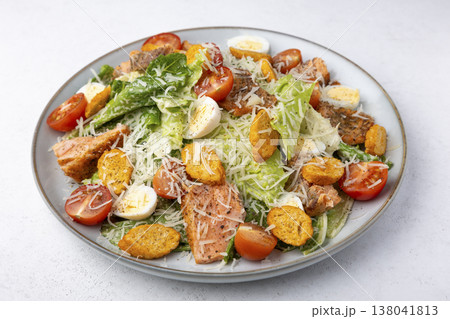 Caesar salad with trout (salmon), cherry tomatoes, croutons, parmesan cheese, quail eggs and romaine lettuce. Traditional American dish. Close-up, selective focus. 138041813