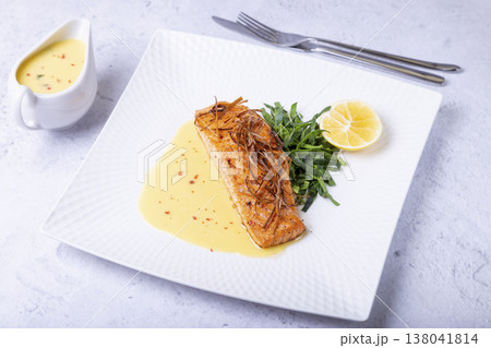 Salmon with beurre blanc sauce, spinach and lemon. Garnished with leeks. Traditional French dish. Close-up. Salmon with beurre blanc sauce, spinach and lemon. Garnished with leeks. Traditional French dish. Close-up. 138041814