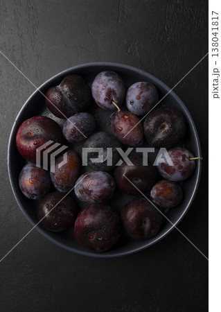 Juicy ripe fresh plum with water drops in gray plate on black background. Seasonal fruits. Selective focus, close-up. Juicy ripe fresh plum with water drops in gray plate on black background. Seasonal fruits. Selective focus, close-up. 138041817
