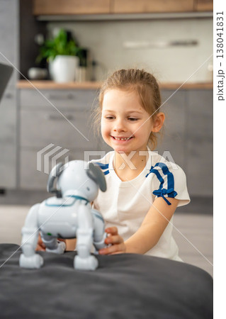 Child playing and interacting with robotic dog on sofa at home. Human robot interaction and digital companionship in modern childhood. 138041831