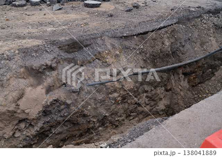 Exposed Underground Utility Conduit Alongside Asphalt With Safety Barriers And Loose Soil Layers Exposed Underground Utility Conduit Alongside Asphalt With Safety Barriers And Loose Soil Layers 138041889