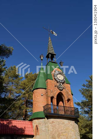 Ancient Brickbuilt Tower Featuring Ornamental Weather Vane Set Against Clear Blue Sky And Tall Pine Trees Ancient Brickbuilt Tower Featuring Ornamental Weather Vane Set Against Clear Blue Sky And Tall Pine Trees 138041904