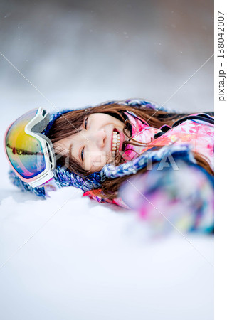 雪の上で寝そべる若い女性 138042007