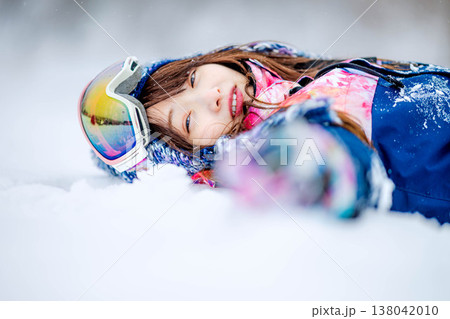 雪の上で寝そべる若い女性 138042010
