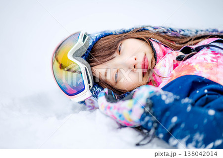 雪の上で寝そべる若い女性 138042014