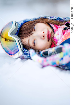 雪の上で寝そべる若い女性 138042016