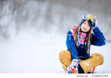 雪の上に座るスキーウェア姿の若い女性 138042264