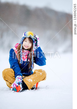 雪の上に座るスキーウェア姿の若い女性 雪の上に座るスキーウェア姿の若い女性 138042265