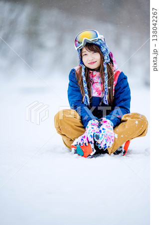 雪の上に座るスキーウェア姿の若い女性 138042267