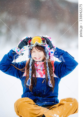 雪の上に座るスキーウェア姿の若い女性 雪の上に座るスキーウェア姿の若い女性 138042275