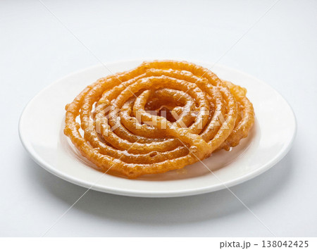 Traditional indian jalebi sweet spiral fried pastry on white plate, close-up studio shot, indian food Traditional indian jalebi sweet spiral fried pastry on white plate, close-up studio shot, indian food 138042425