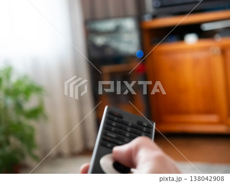 Person holding remote control pointing at television screen. Watching media entertainment at home. Leisure activity in living room, relaxation concept. Broadcasting channel changing device. Person holding remote control pointing at television screen. Watching media entertainment at home. Leisure activity in living room, relaxation concept. Broadcasting channel changing device. 138042908