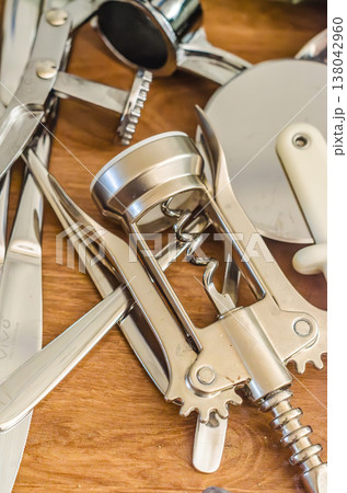 Close up of various stainless steel kitchen utensils on a wooden table, including a corkscrew. Close up of various stainless steel kitchen utensils on a wooden table, including a corkscrew. 138042960