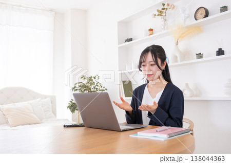 オンライン会議でパソコンに向かって話す20代女性 138044363